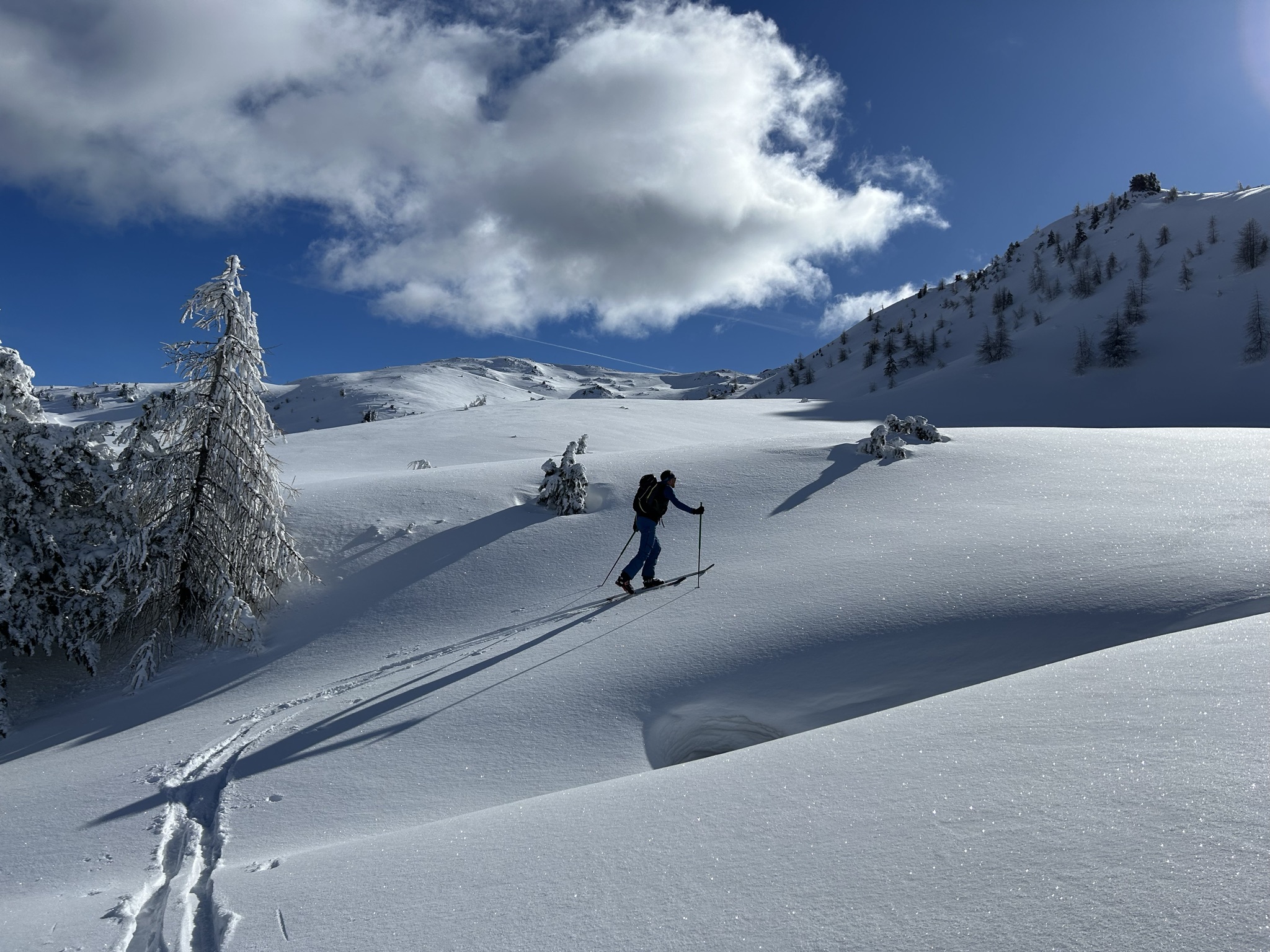 Ski tourer ascending across a wide, untouched snowfield