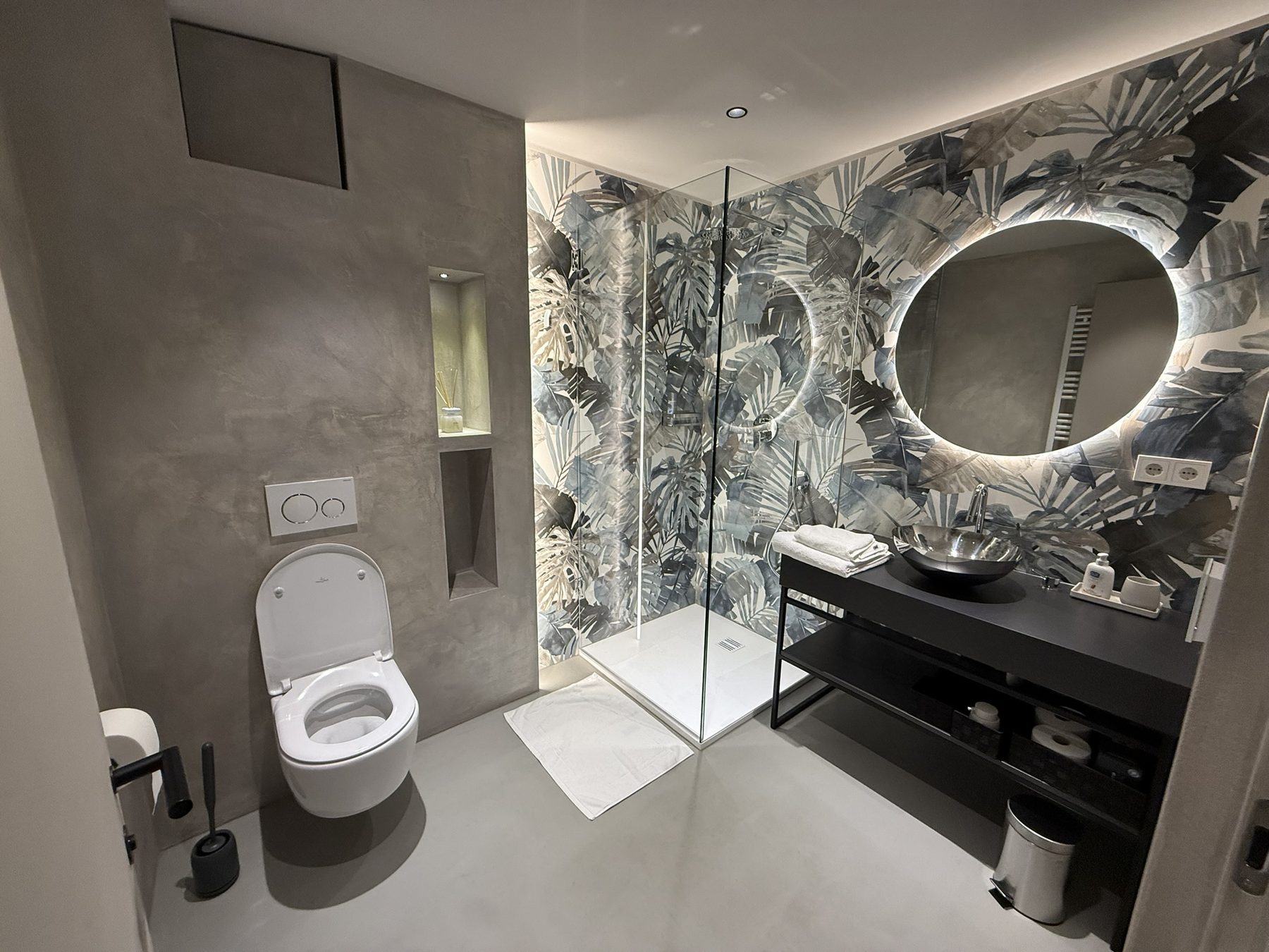 Bagno con parete a motivo fogliato e doccia walk-in