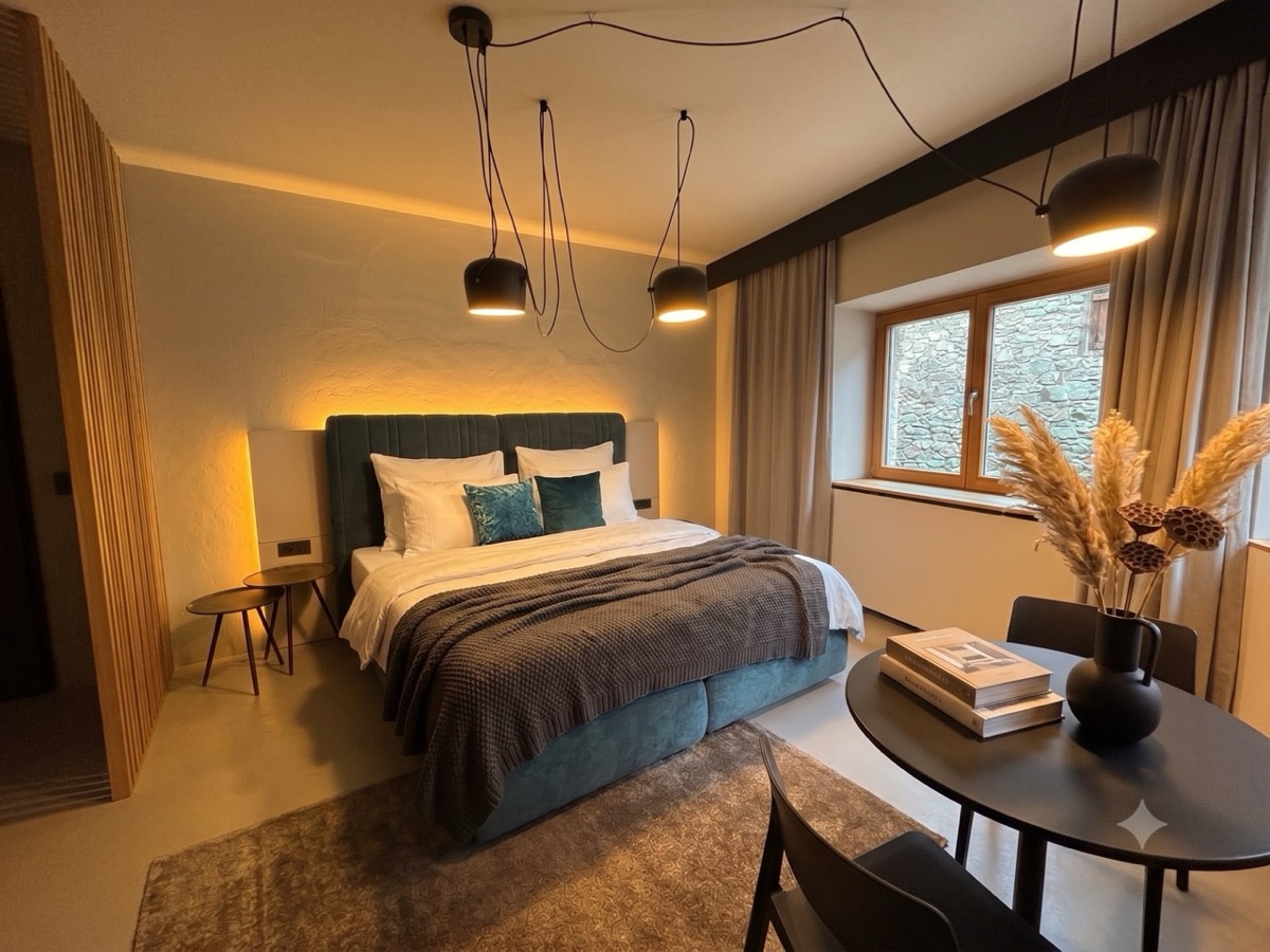 Seconda camera da letto con letto imbottito verde e vista dalla finestra sul muro in pietra