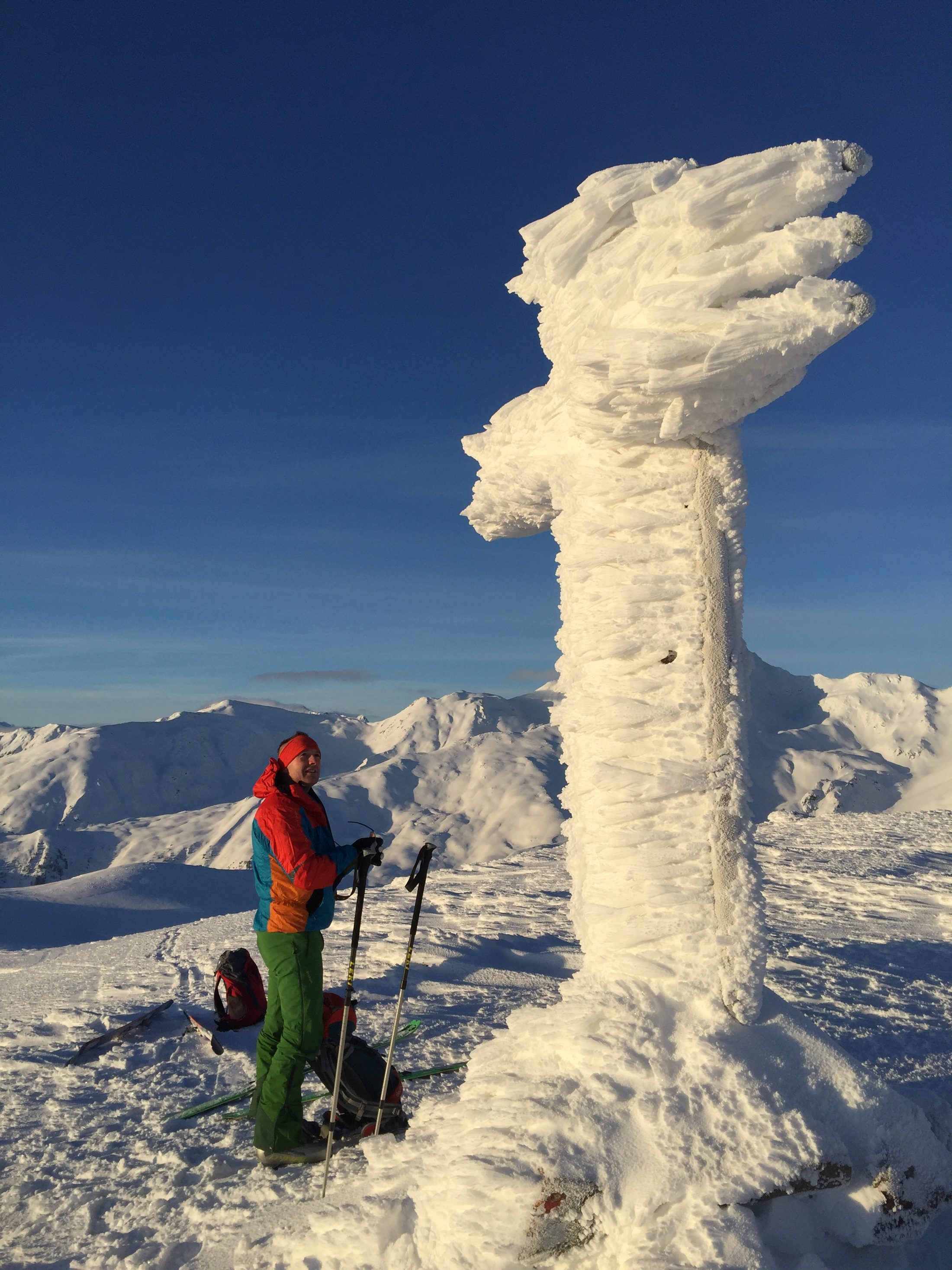 Ski tourer beside a wind-sculpted snow formation in the mountains